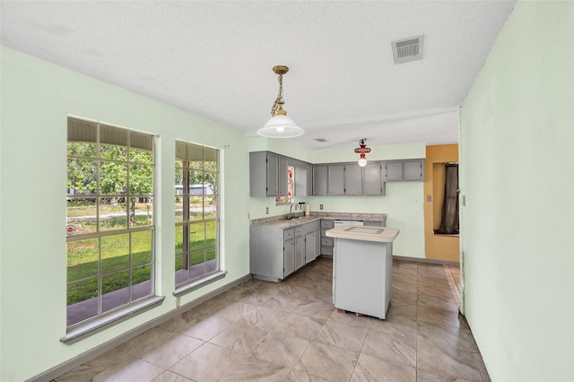 20983 Westgrove Ln, Porter, TX 77365 - kitchen with a sink, visible vents, light countertops, a center island, and gray cabinetry