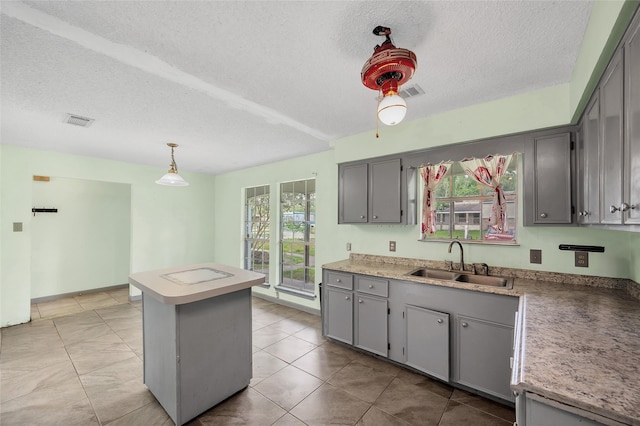 20983 Westgrove Ln, Porter, TX 77365 - kitchen with a sink, a textured ceiling, visible vents, a center island, and gray cabinetry