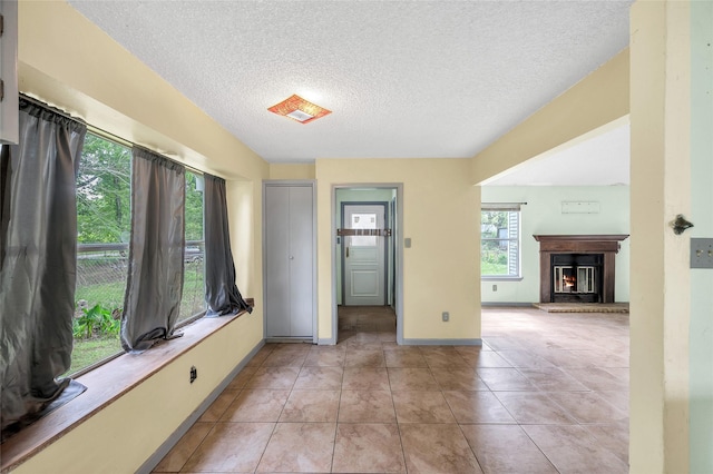 20983 Westgrove Ln, Porter, TX 77365 - foyer with a textured ceiling, baseboards, light tile patterned floors, and a glass covered fireplace