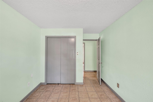 20983 Westgrove Ln, Porter, TX 77365 - unfurnished bedroom with light tile patterned floors, baseboards, a closet, and a textured ceiling