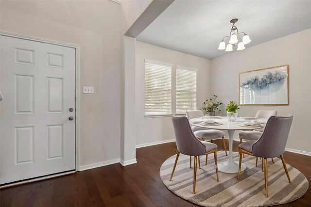 dining area featuring baseboards, wood finished floors, and an inviting chandelier