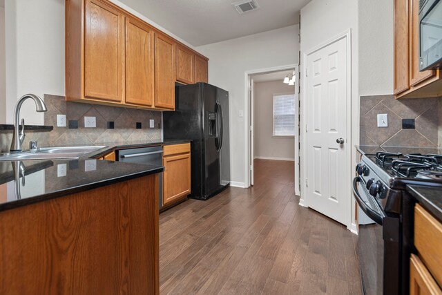 kitchen featuring brown cabinets, dark wood-style flooring, a sink, visible vents, and black appliances