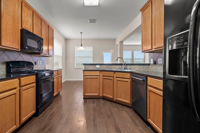 kitchen with a sink, tasteful backsplash, black appliances, and dark wood-style flooring