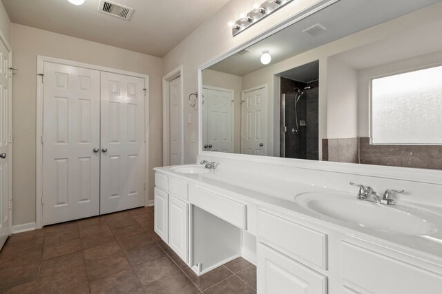 full bathroom featuring double vanity, visible vents, a sink, and a shower
