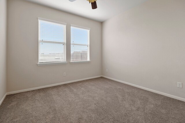 carpeted empty room featuring baseboards and a ceiling fan