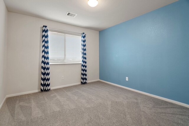 carpeted empty room with visible vents and baseboards