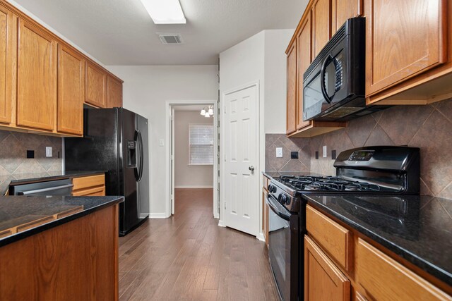 kitchen with brown cabinets, black appliances, dark wood finished floors, and visible vents