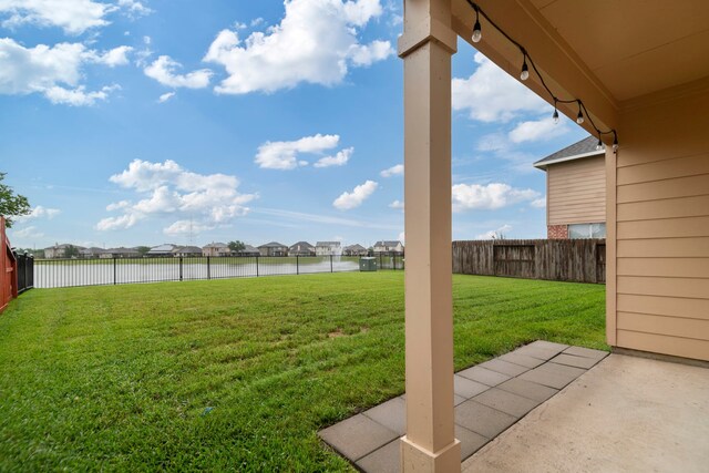 view of yard featuring a water view, a patio area, a fenced backyard, and a residential view