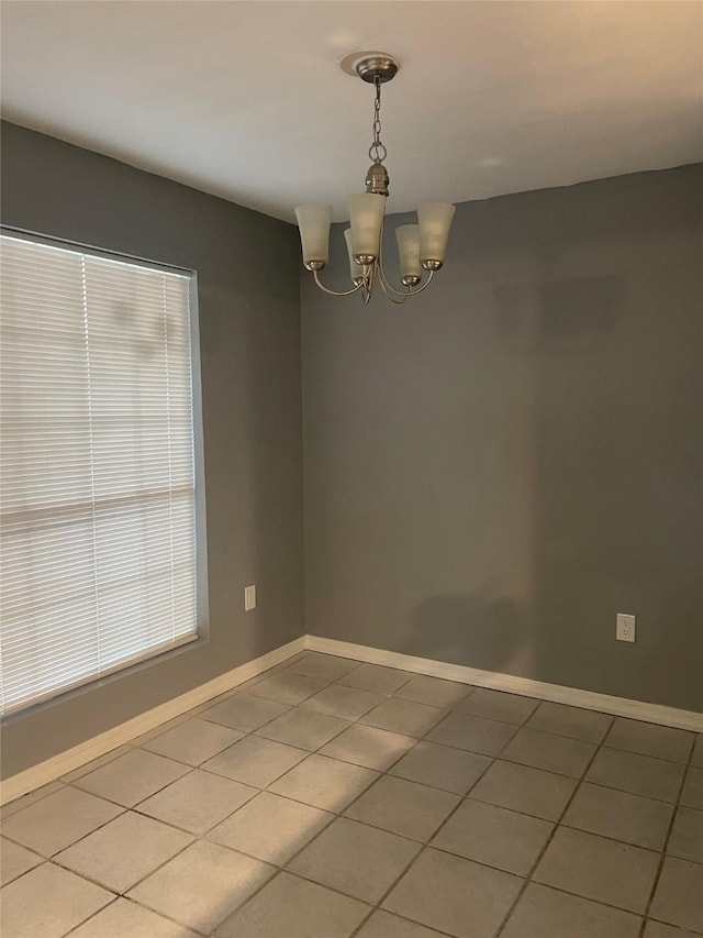 spare room featuring light tile patterned floors, a chandelier, and baseboards