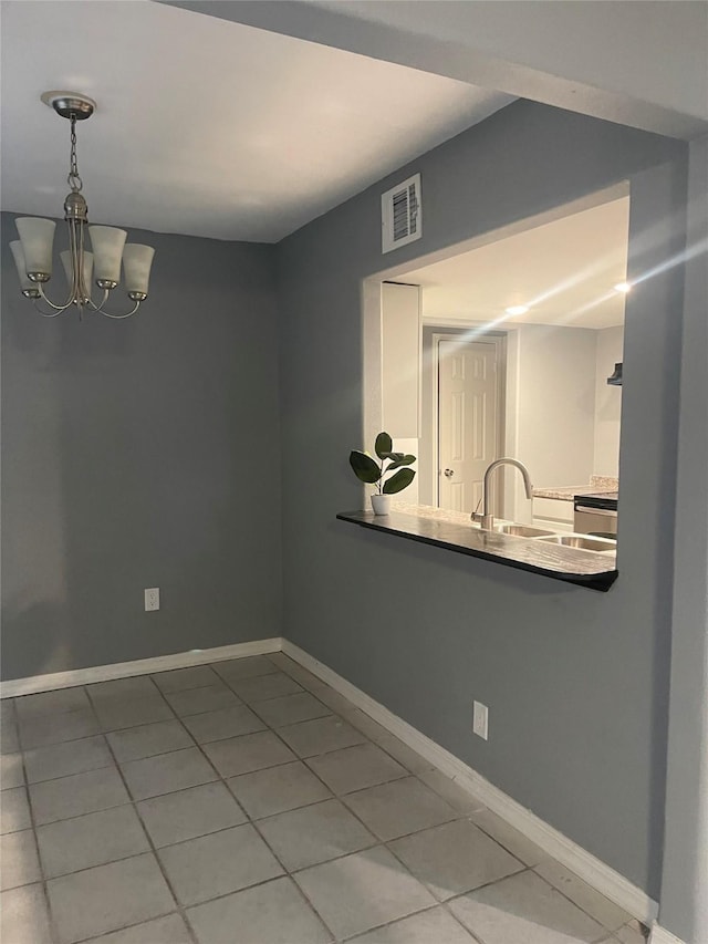 unfurnished dining area with tile patterned floors, baseboards, a sink, and a chandelier