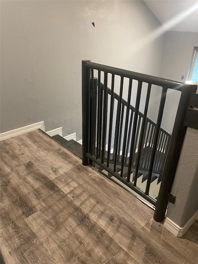 staircase with wood finished floors, baseboards, and lofted ceiling