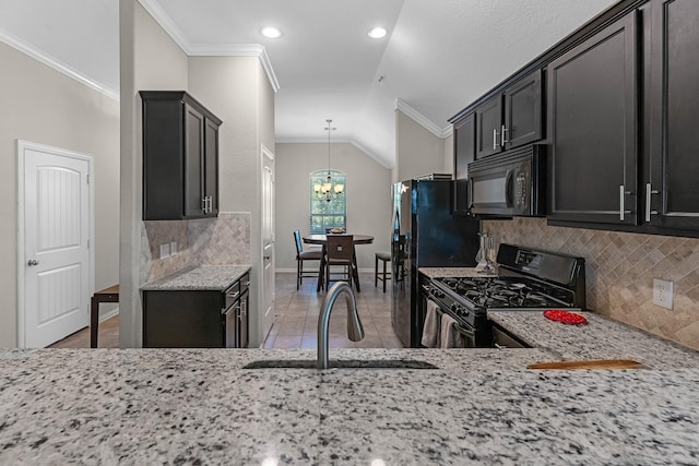 kitchen with light stone counters, tasteful backsplash, a sink, black appliances, and ornamental molding