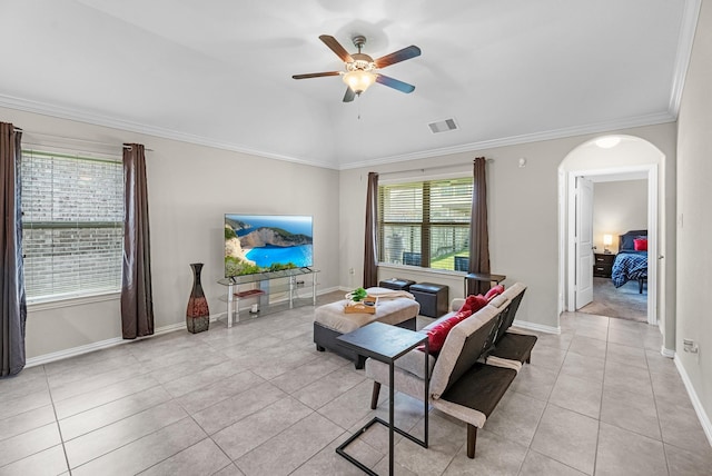 living room with light tile patterned flooring, arched walkways, a ceiling fan, and plenty of natural light
