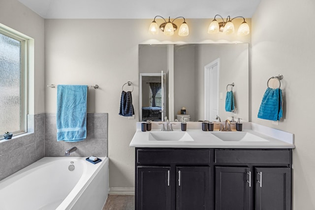 bathroom with baseboards, a bath, double vanity, and a sink
