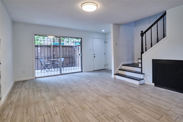 2574 Marilee Ln Unit 1, Houston, TX 77057 - unfurnished living room with baseboards, light wood-style flooring, and stairs