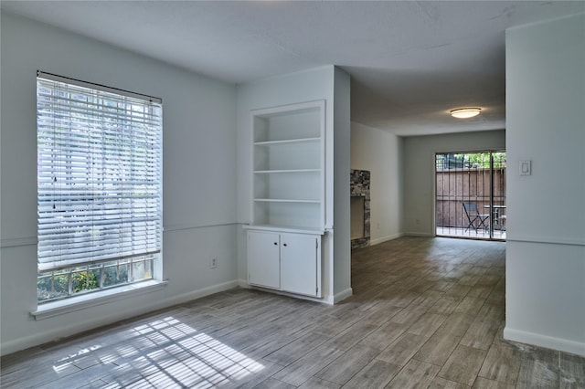 2574 Marilee Ln Unit 1, Houston, TX 77057 - spare room featuring baseboards, a fireplace, and light wood-type flooring
