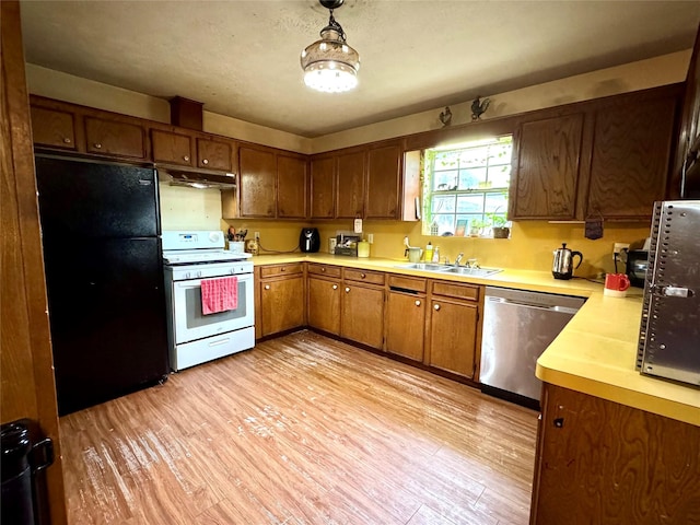 kitchen featuring a sink, white gas range oven, under cabinet range hood, dishwasher, and freestanding refrigerator