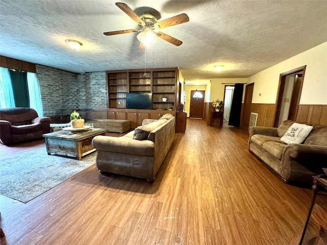 living room with a textured ceiling, wainscoting, and wood finished floors