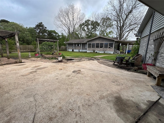 view of yard with fence, a pergola, a patio area, and a sunroom