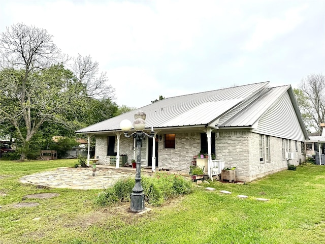 view of front of property with metal roof, a front lawn, a patio, and brick siding