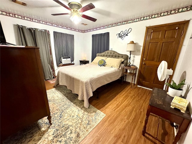 bedroom with a ceiling fan, visible vents, and wood finished floors