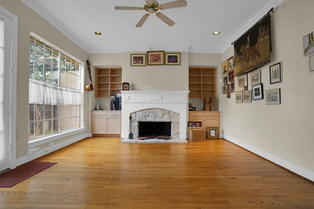 unfurnished living room with ornamental molding, baseboards, a stone fireplace, ceiling fan, and light wood-type flooring