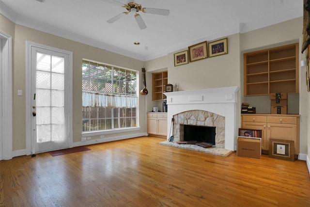 unfurnished living room with a ceiling fan, crown molding, a fireplace, baseboards, and light wood-style flooring