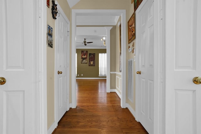 hallway with baseboards, ornamental molding, and dark wood-type flooring