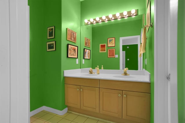 bathroom with baseboards, double vanity, tile patterned floors, and a sink
