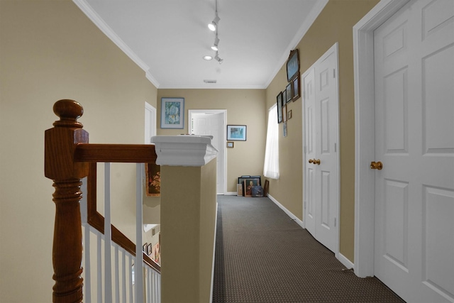 hallway with visible vents, ornamental molding, track lighting, dark colored carpet, and baseboards