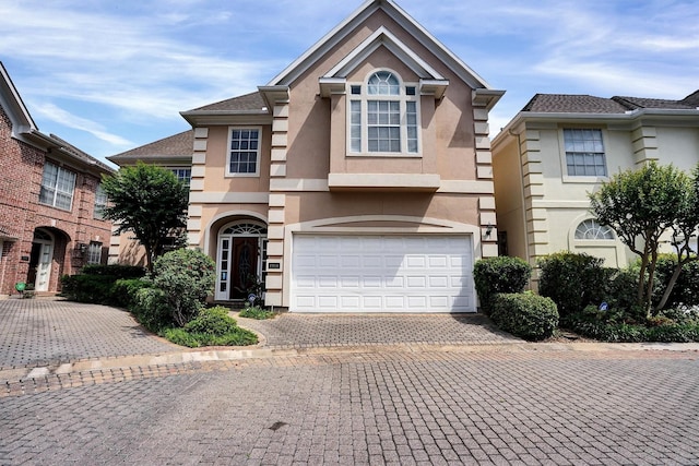 traditional-style home featuring stucco siding, an attached garage, and driveway
