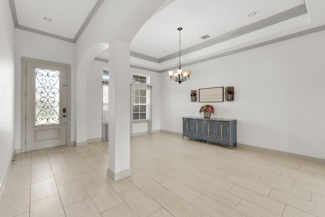 entrance foyer with an inviting chandelier, a tray ceiling, baseboards, ornamental molding, and arched walkways
