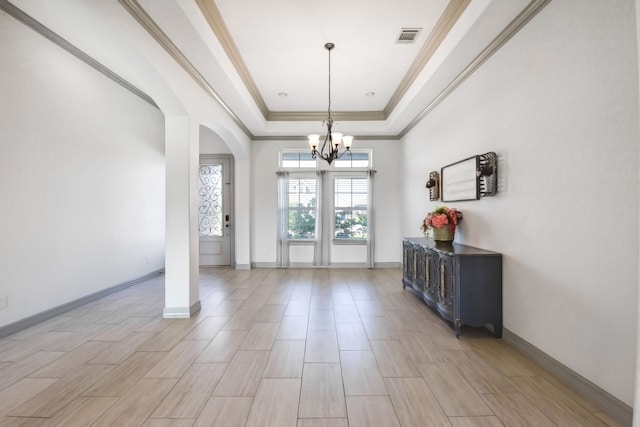 foyer entrance with a notable chandelier, a raised ceiling, visible vents, baseboards, and arched walkways