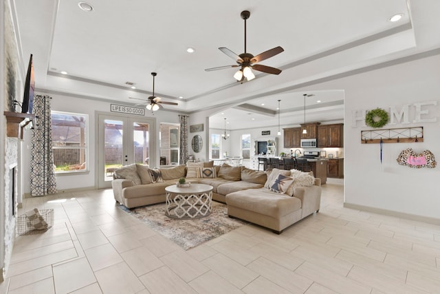 living area featuring recessed lighting, a raised ceiling, a ceiling fan, baseboards, and arched walkways