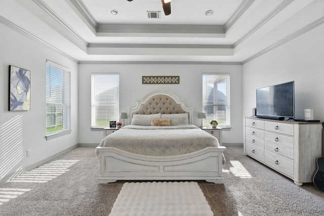 carpeted bedroom with visible vents, ornamental molding, a tray ceiling, and baseboards