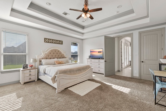 bedroom with a raised ceiling, visible vents, baseboards, arched walkways, and light colored carpet