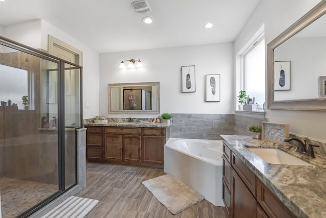 full bathroom featuring a garden tub, a stall shower, a sink, and visible vents