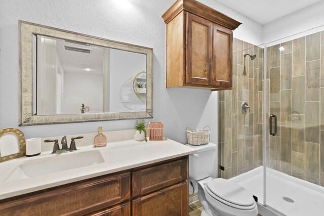 full bathroom with toilet, vanity, a shower stall, and visible vents