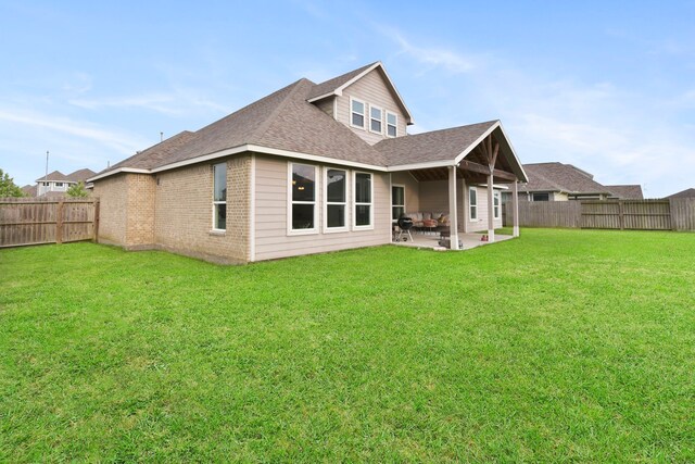 rear view of property with a patio, a lawn, a fenced backyard, and roof with shingles