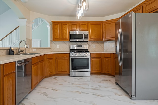 11911 Timpnogos Dr, Tomball, TX 77377 - kitchen with ornate columns, appliances with stainless steel finishes, brown cabinetry, and a sink