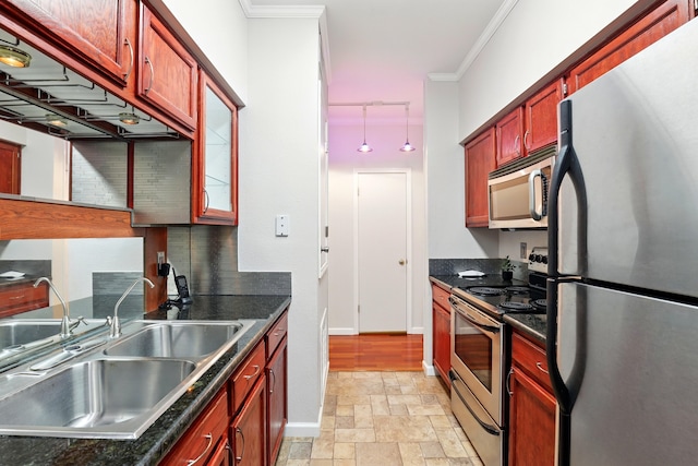 kitchen featuring dark countertops, stainless steel appliances, stone tile flooring, and a sink