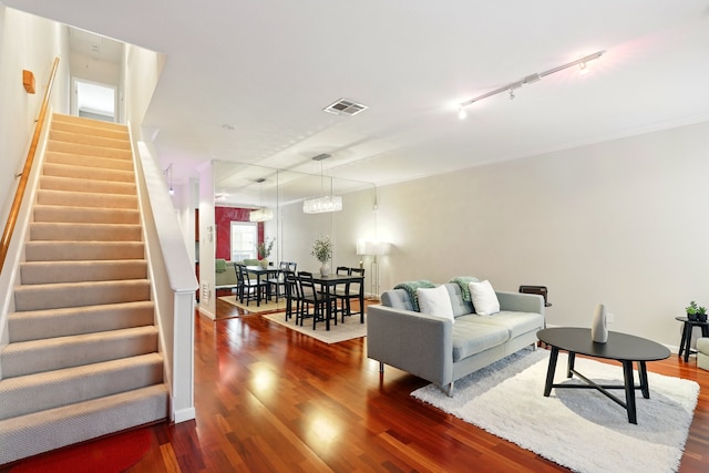 living room featuring track lighting, visible vents, wood finished floors, and stairway