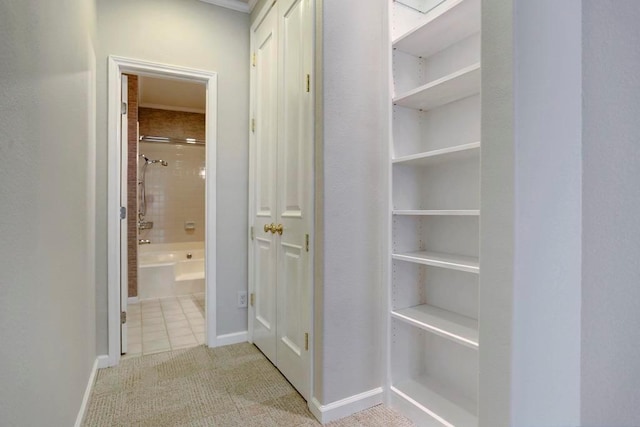hallway featuring baseboards and light colored carpet