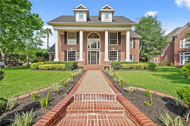 greek revival inspired property featuring a front lawn and brick siding