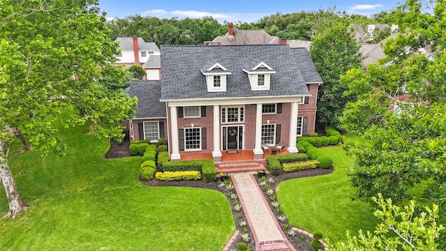neoclassical / greek revival house featuring brick siding, roof with shingles, and a front lawn