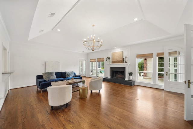 living area with visible vents, wood finished floors, recessed lighting, a fireplace with raised hearth, and a notable chandelier