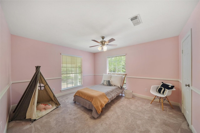 carpeted bedroom featuring baseboards, a ceiling fan, and visible vents