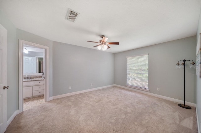 unfurnished bedroom featuring visible vents, a sink, baseboards, and light colored carpet