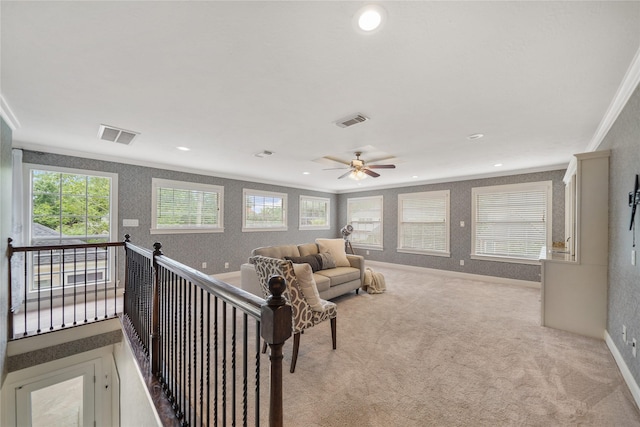 living room with crown molding, wallpapered walls, visible vents, and light carpet