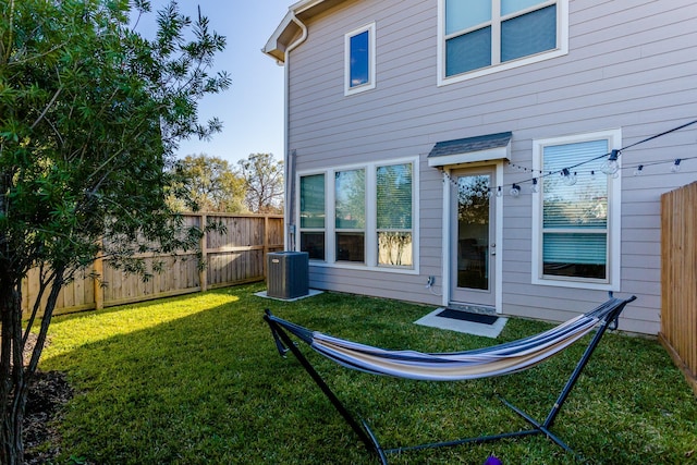 back of property with a lawn, a fenced backyard, and central air condition unit